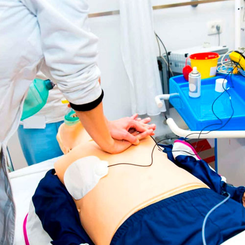Medical professional performing CPR on a training manikin in a hospital setting
