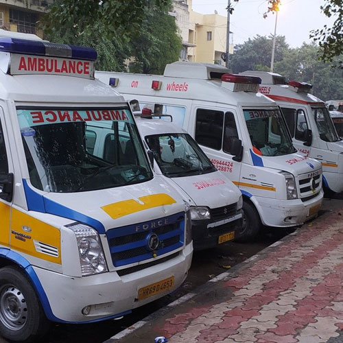 Row of white and yellow emergency vehicles, displaying AMBULANCE signage.