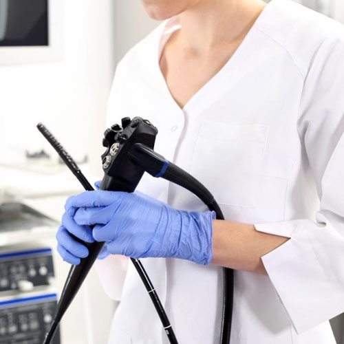 A healthcare professional in gloves holds a medical endoscope, ready for a procedure in a clinical setting.