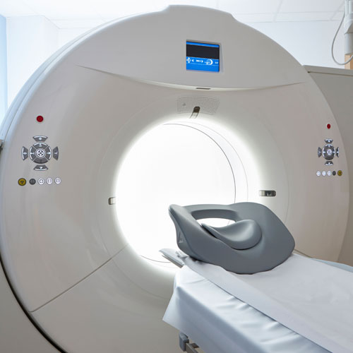Close-up of a modern CT scanner gantry with its illuminated opening and the patient table extended