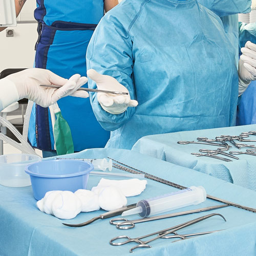 Surgeons in sterile gowns preparing surgical instruments in operating room – focus on surgical tools and sterile technique