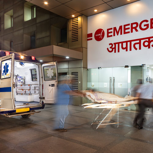 Emergency staff moving a patient on a stretcher from an ambulance into a hospital at night