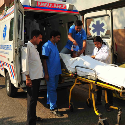 Medical team attending to a patient on a stretcher beside an ambulance during emergency care