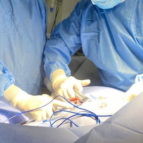 Surgeons in blue sterile suits performing a surgical procedure.
